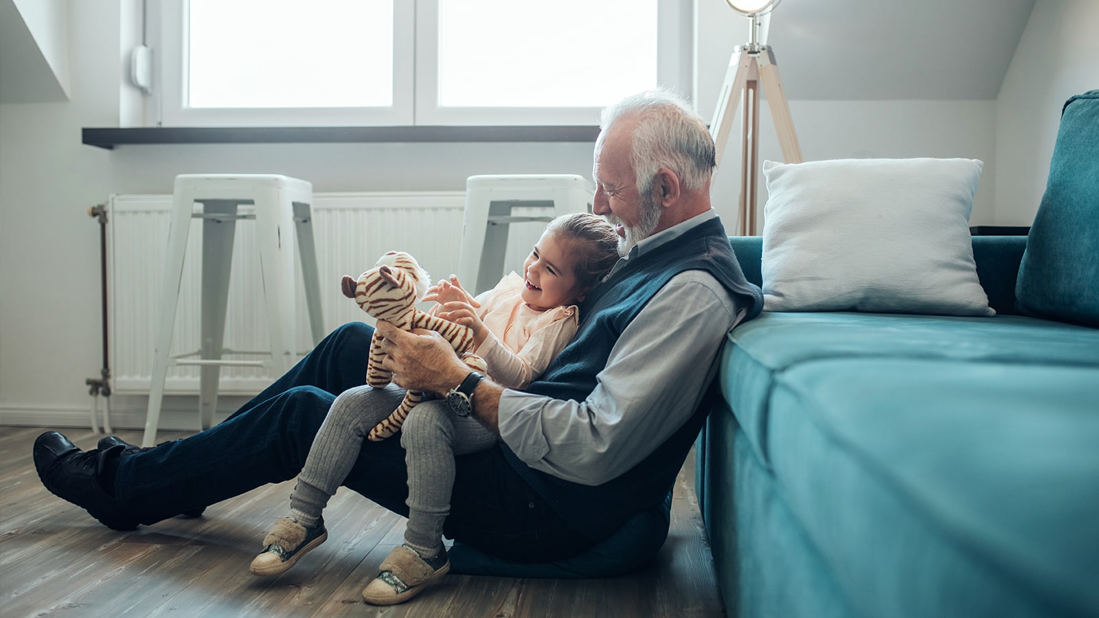 Grandfather and grandchild play with a stuffed animal