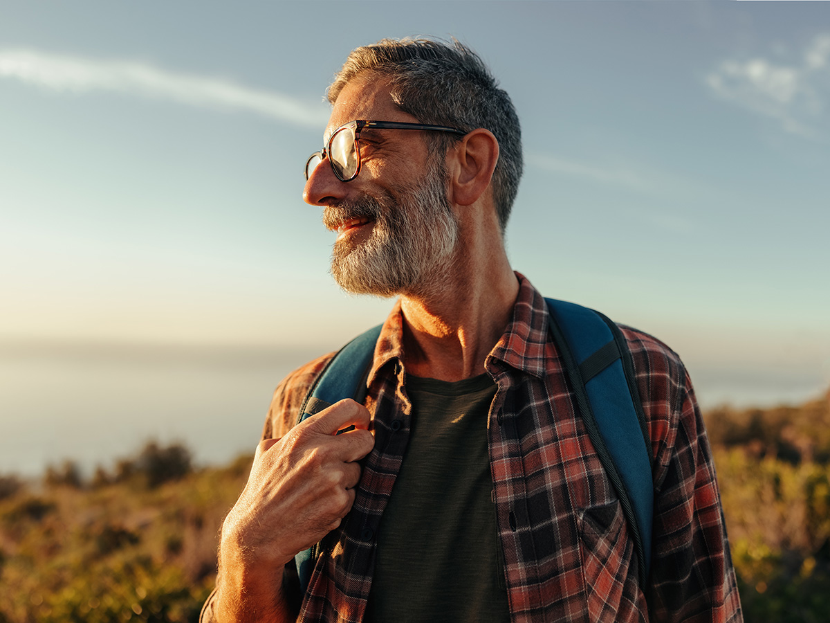 Older man in glasses and backpack hikes outdoors