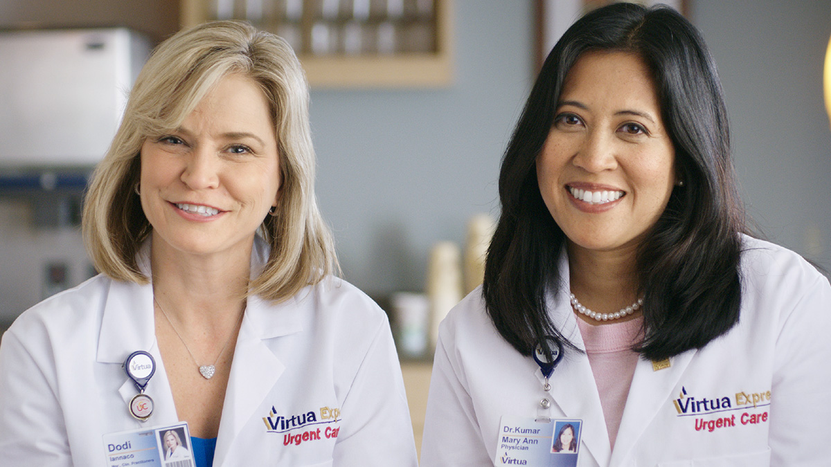 Virtua Medical Group incorporated in 2009. Two of Virtua's female clinicians are shown in a medical office, smiling for the camera.
