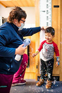 Pediatric Mobile Services woman checking the height of a child