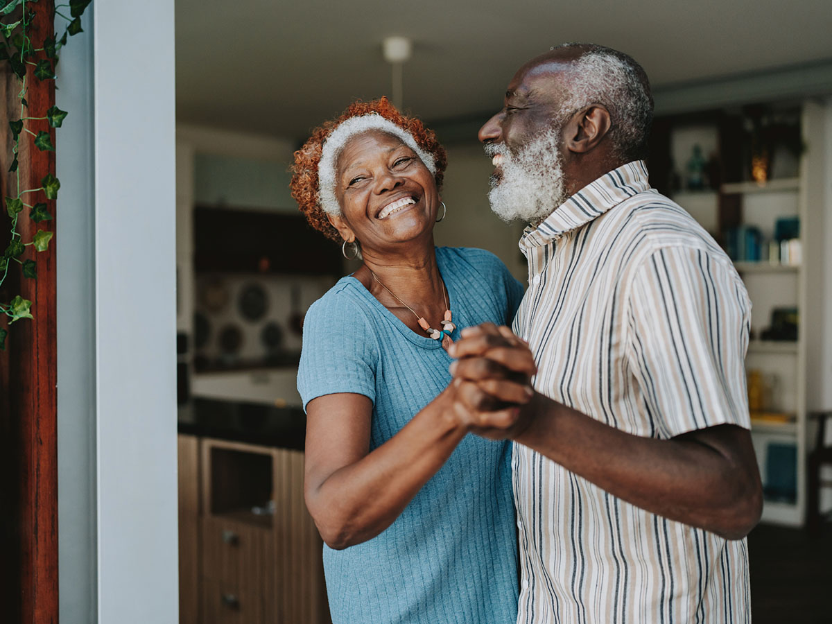 Older senior citizen couple dancing in their living room