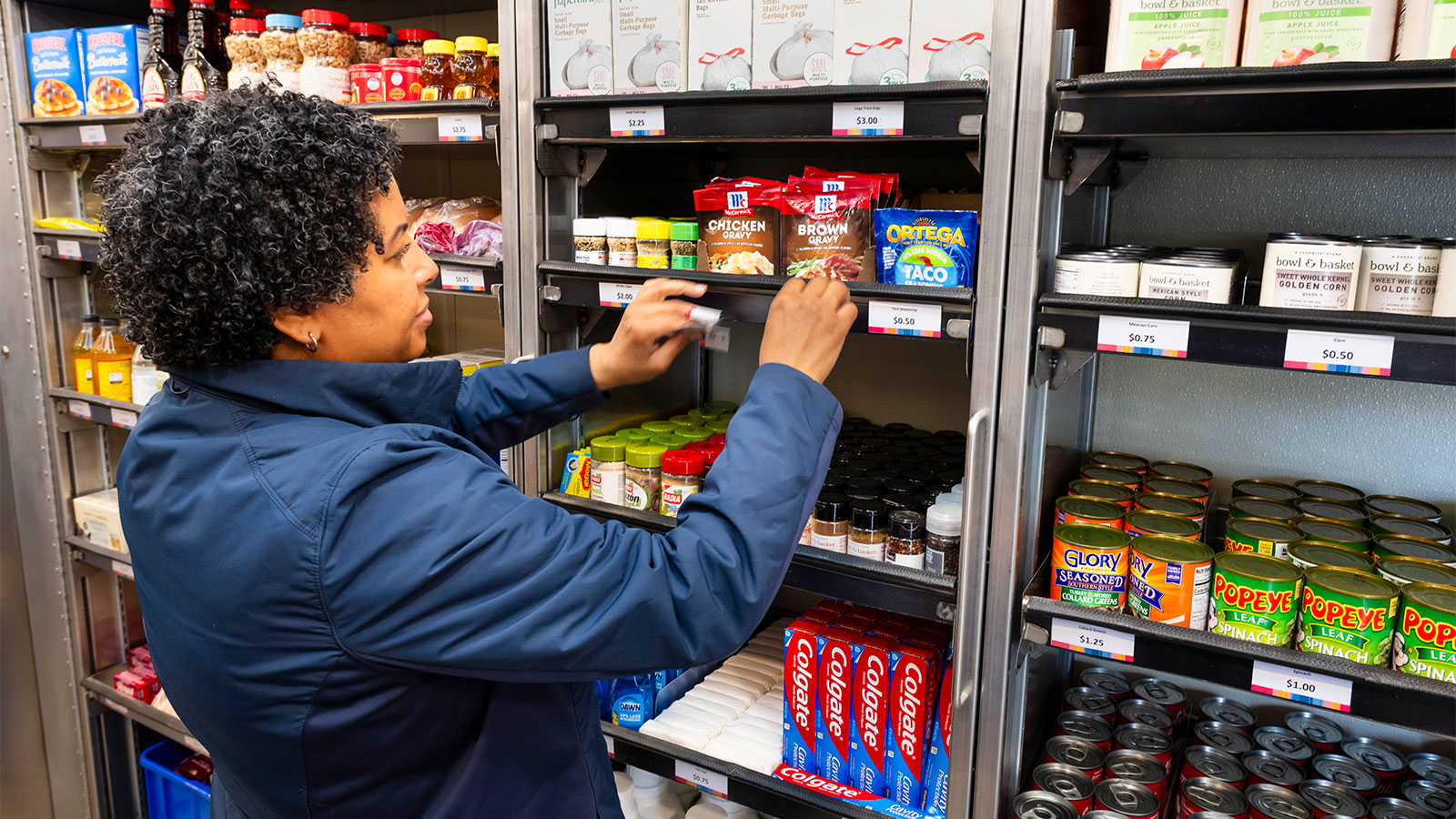 Female Virtua Health employee puts stickers on shelves on Virtua's Mobile Grocery Store