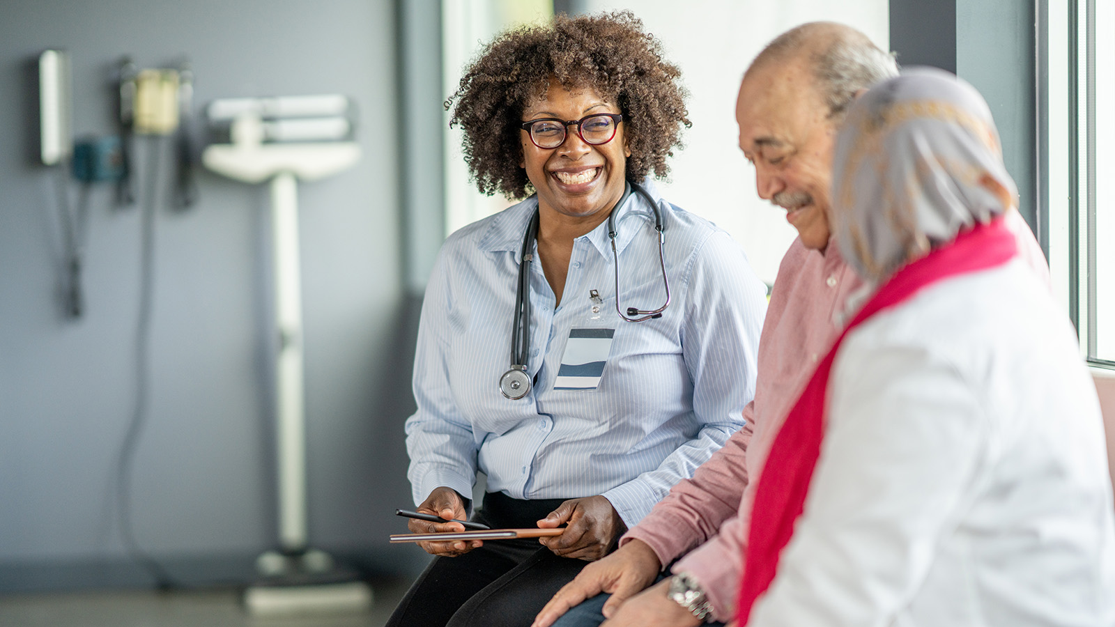 Female doctor smiling and talking to an elderly man and woman