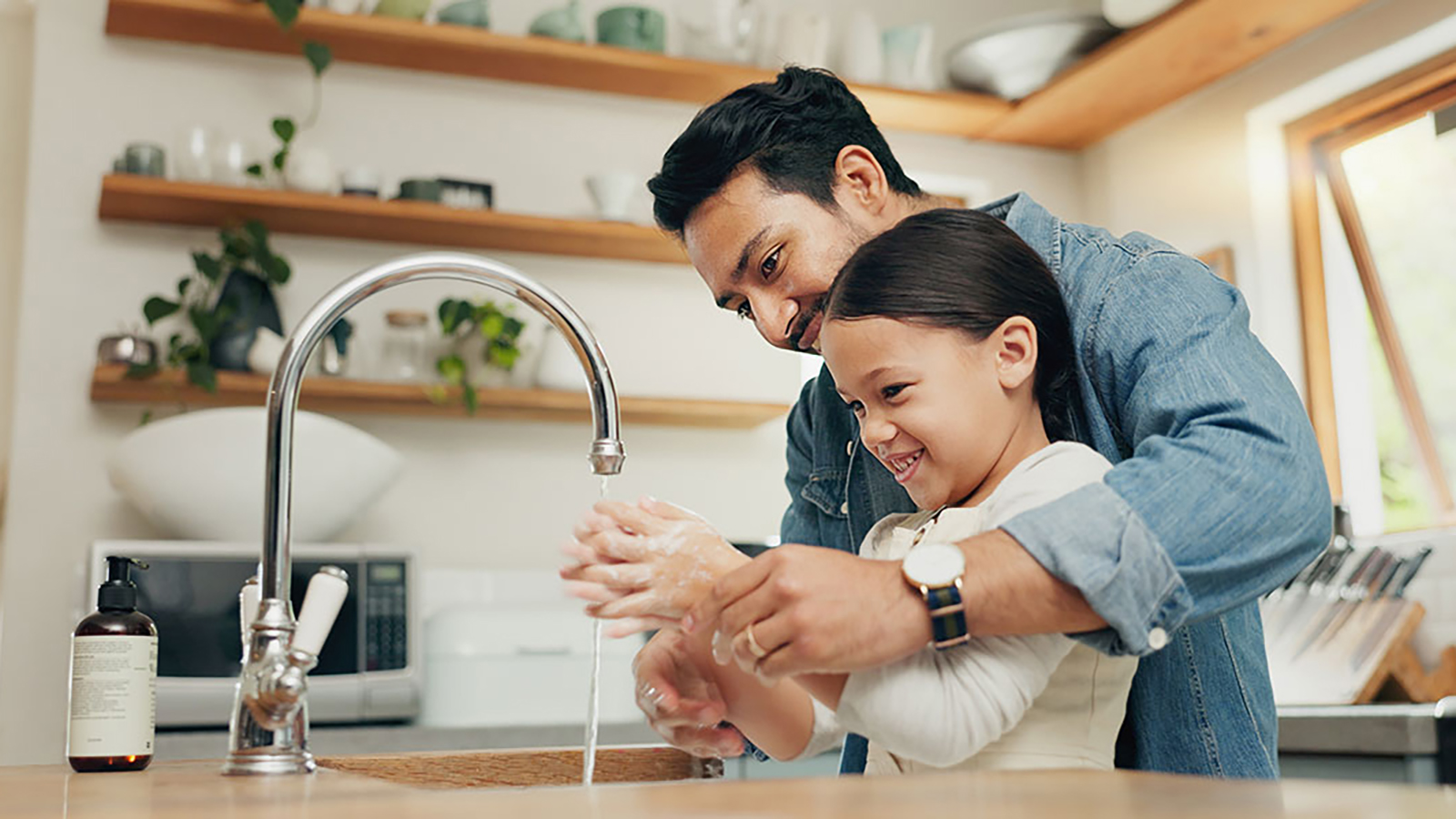 father and daughter washing their hands at the sink