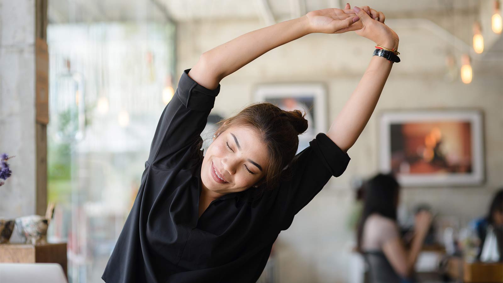 Woman in living room stretching and bending to the side with her arms over her head