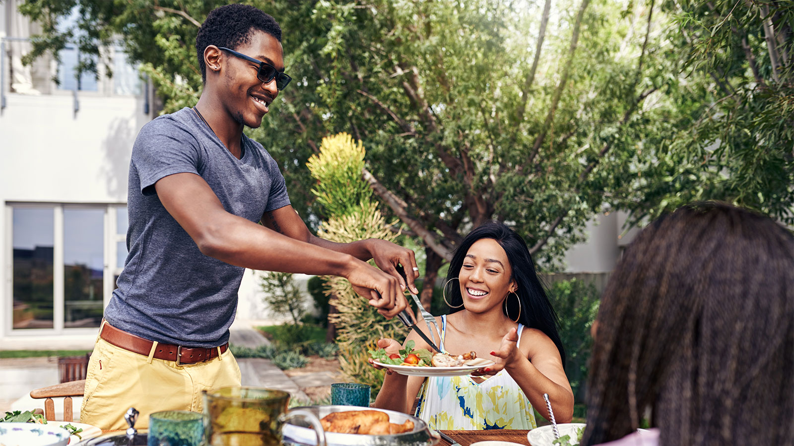 two friends serving barbeque food outside in the summer