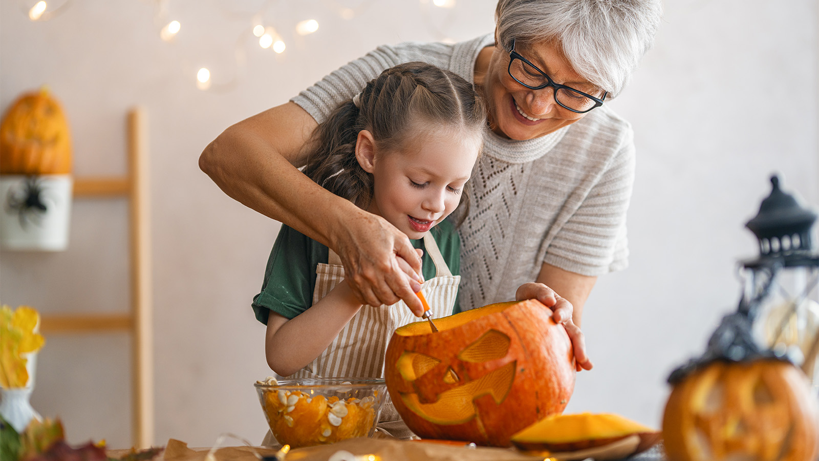 group of children in Halloween costumes smiling and holding pumpkin-shaped candy buckets while trick-or-treating at night.