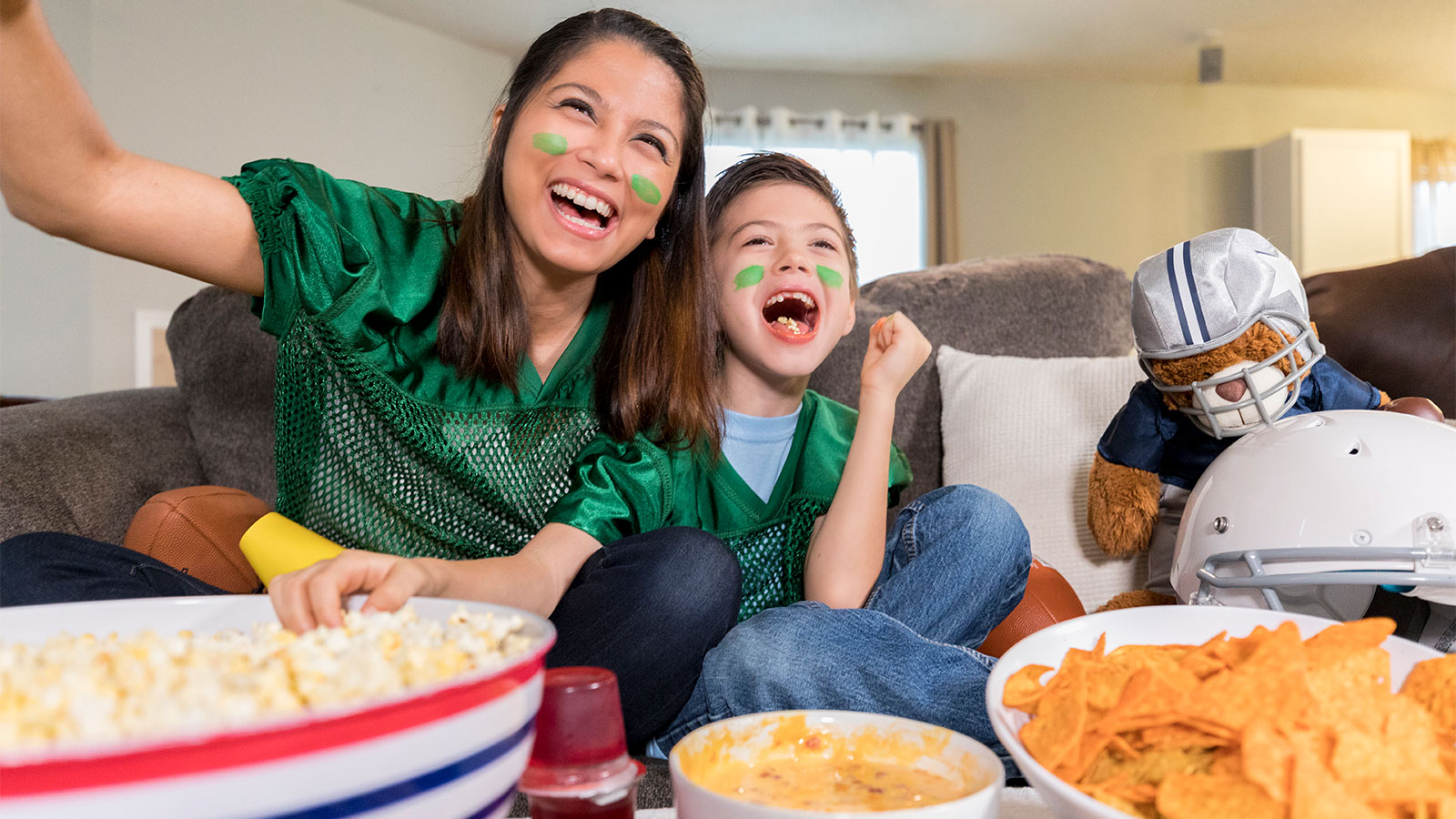 mother and son cheering on a football game while eating snacks