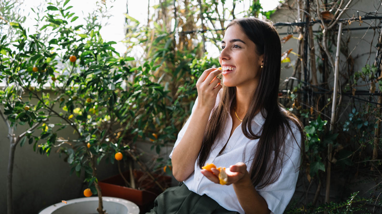 Young woman sitting outside eating a fruit salad