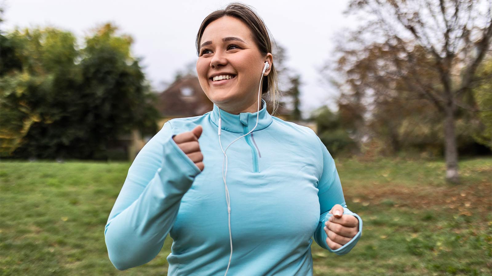 woman listening to music in headphones while taking a jog outside