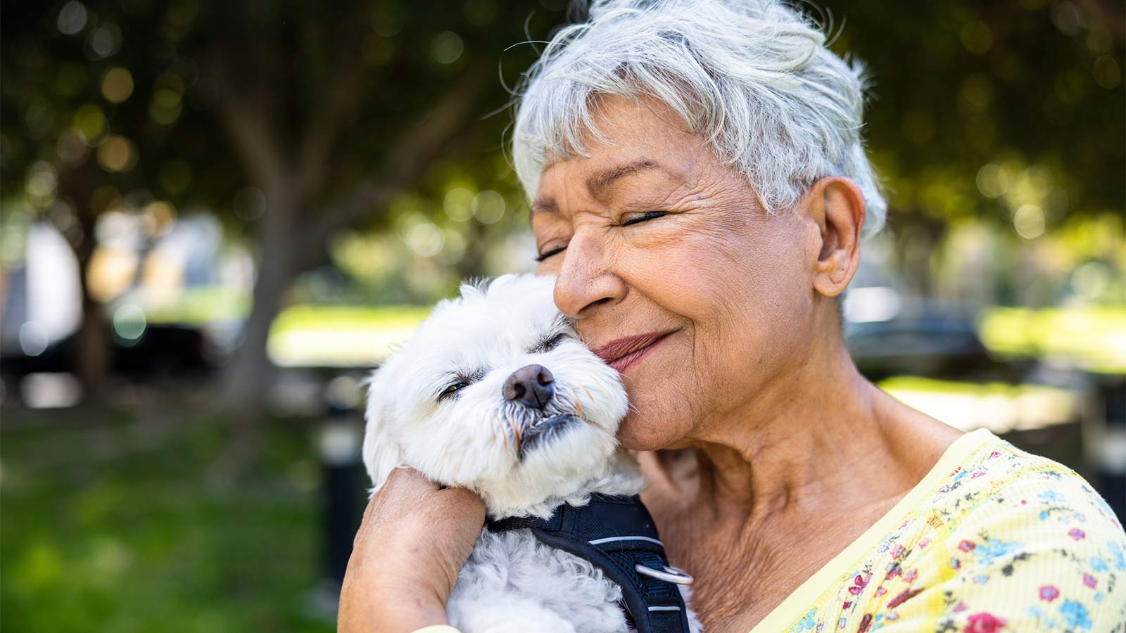elderly woman smiling and holding a small dog