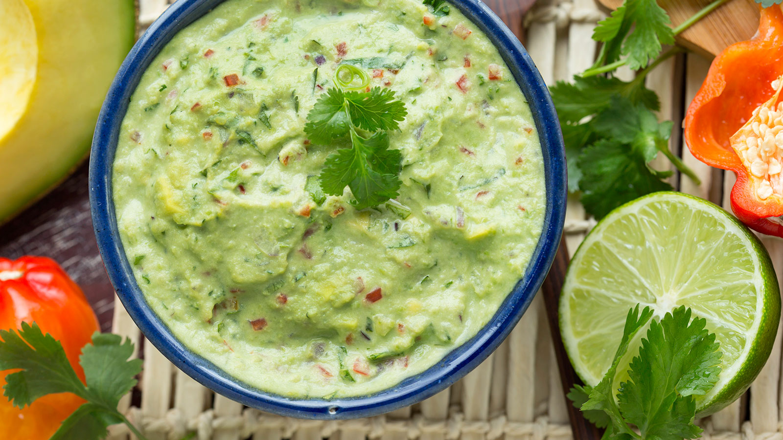 a bowl of guacamole with herbs and lime