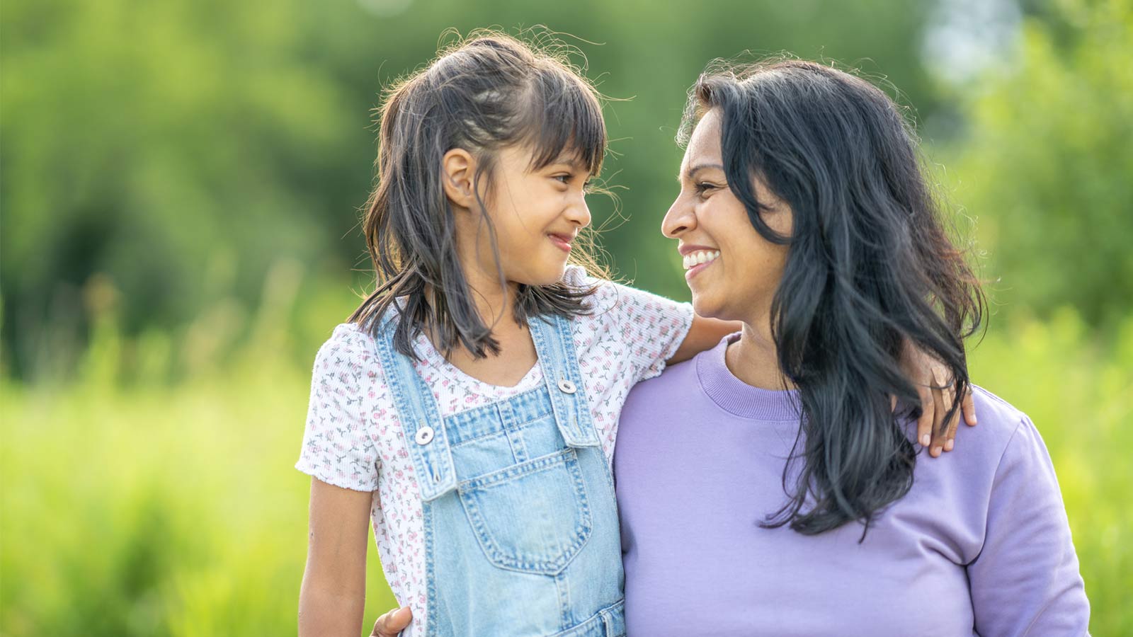 mother and daughter smiling at each other outside in nature