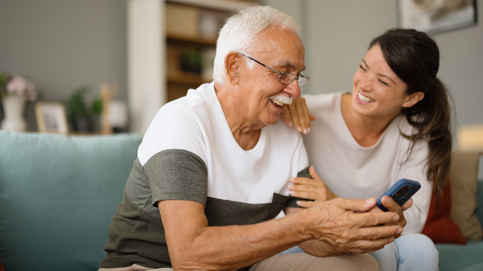 Young adult woman sitting on couch and laughing with older male