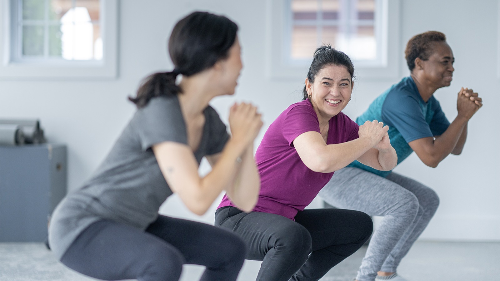 Women doing squats and smiling at each other during an exercise class