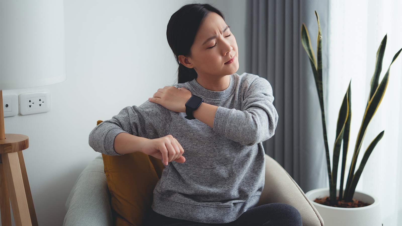 woman sitting in a chair and stretching her shoulder