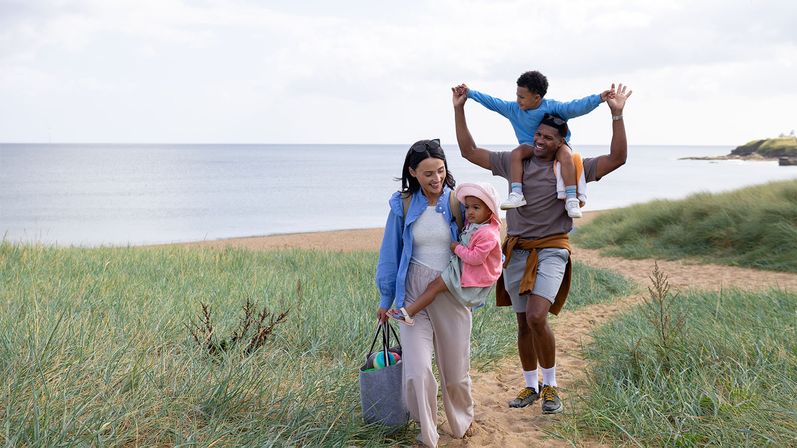 Mom. Dad, young boy and baby girl walking along a path near the ocean
