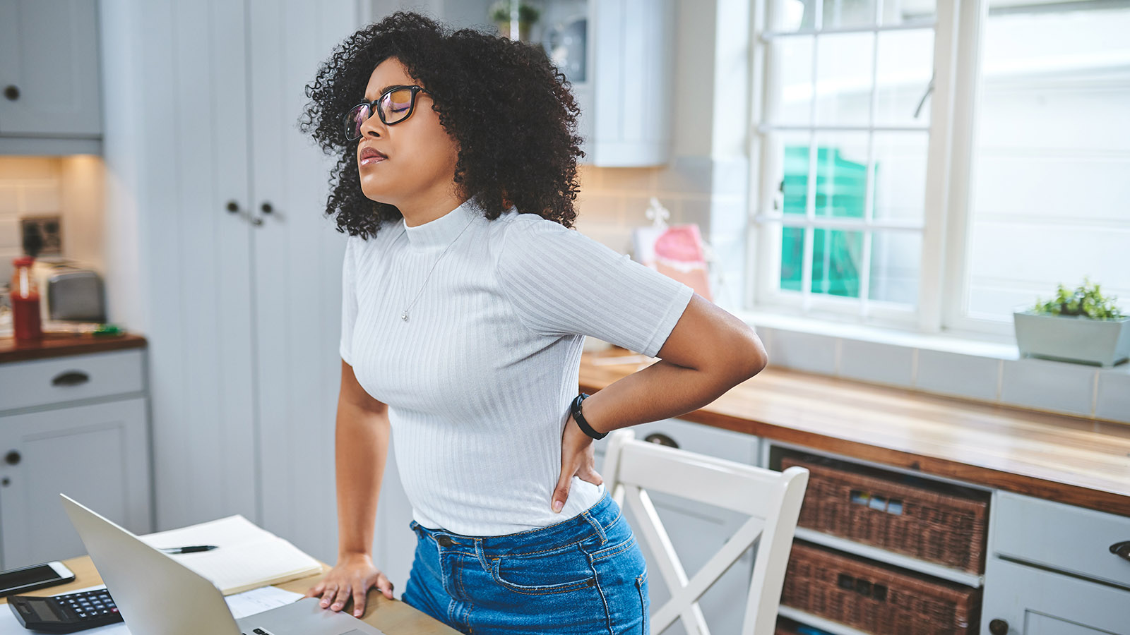 young woman trying to sit comfortable while working with back pain