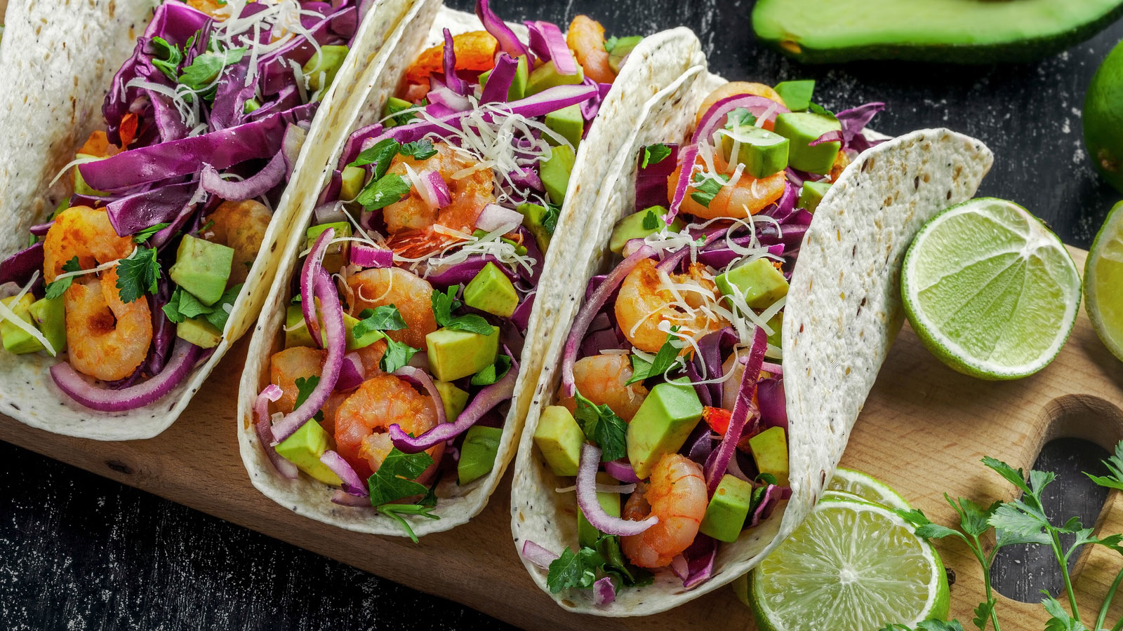 three tacos filled with shrimp and vegetables arranged on a platter