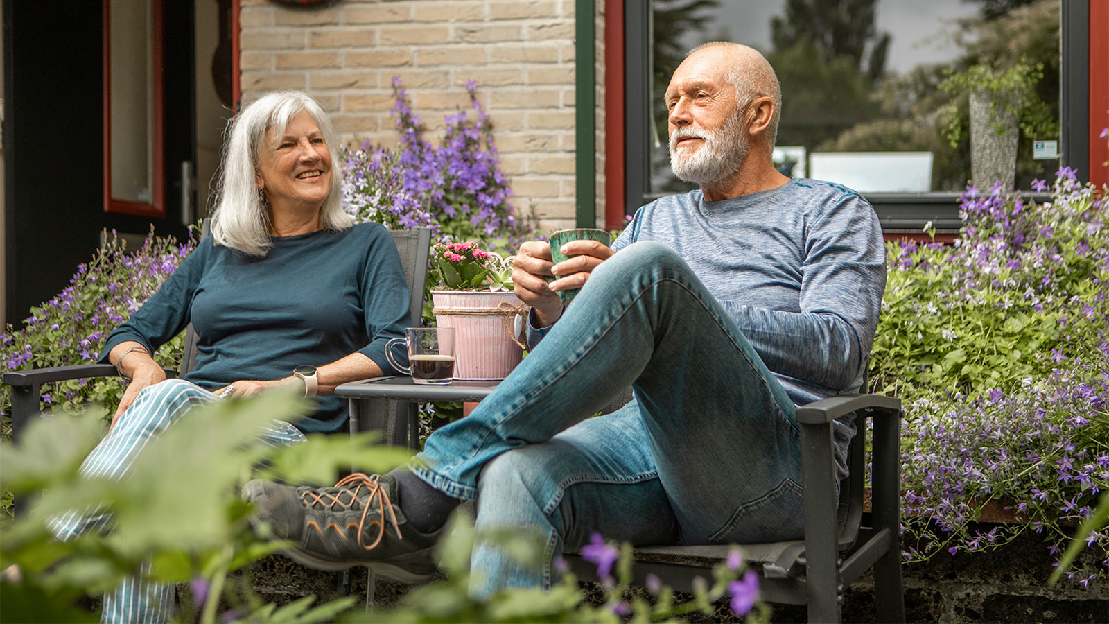 Senior man and woman sitting among purple flowers outdoors
