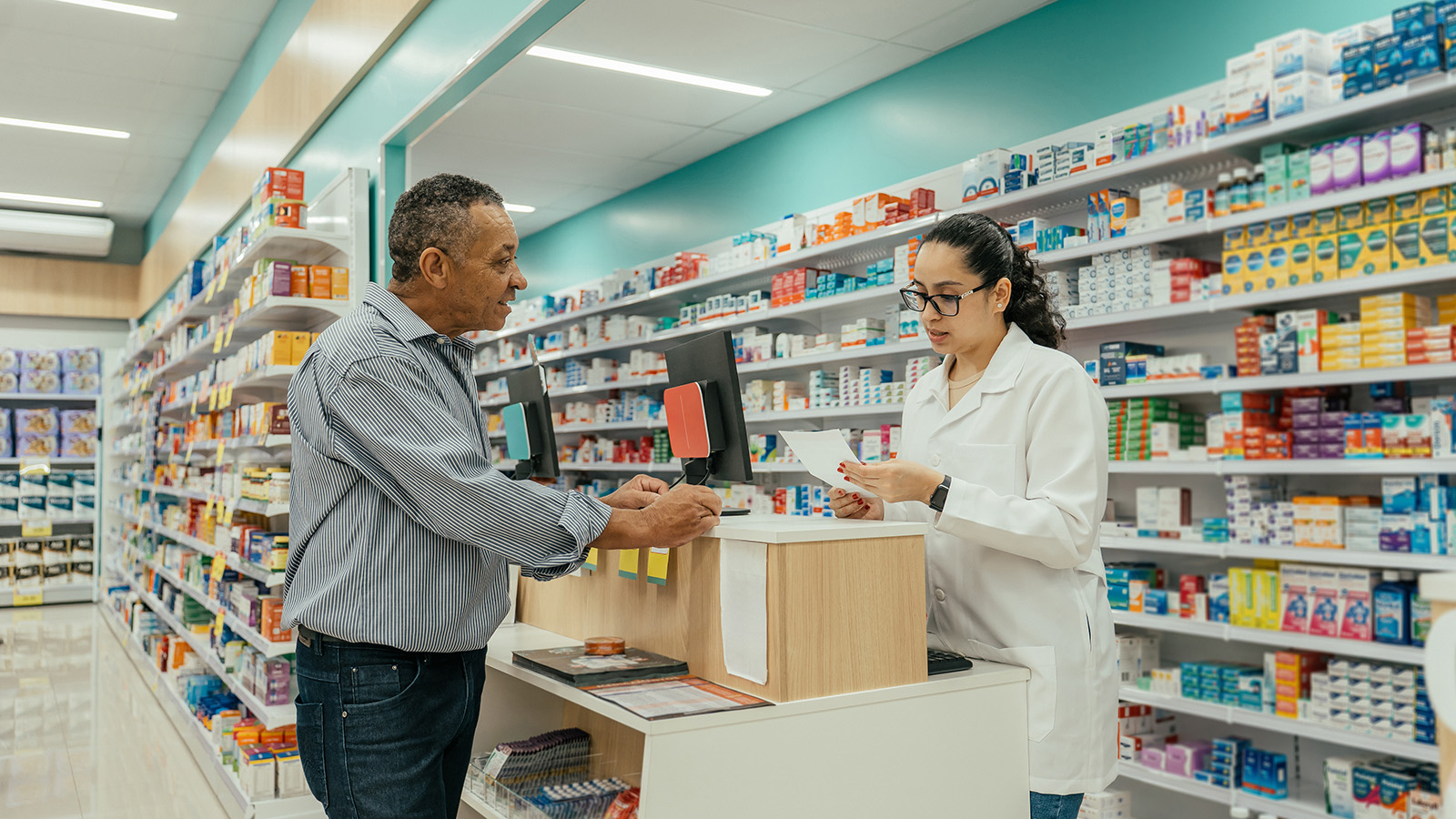 Older male speaking to younger female pharmacist