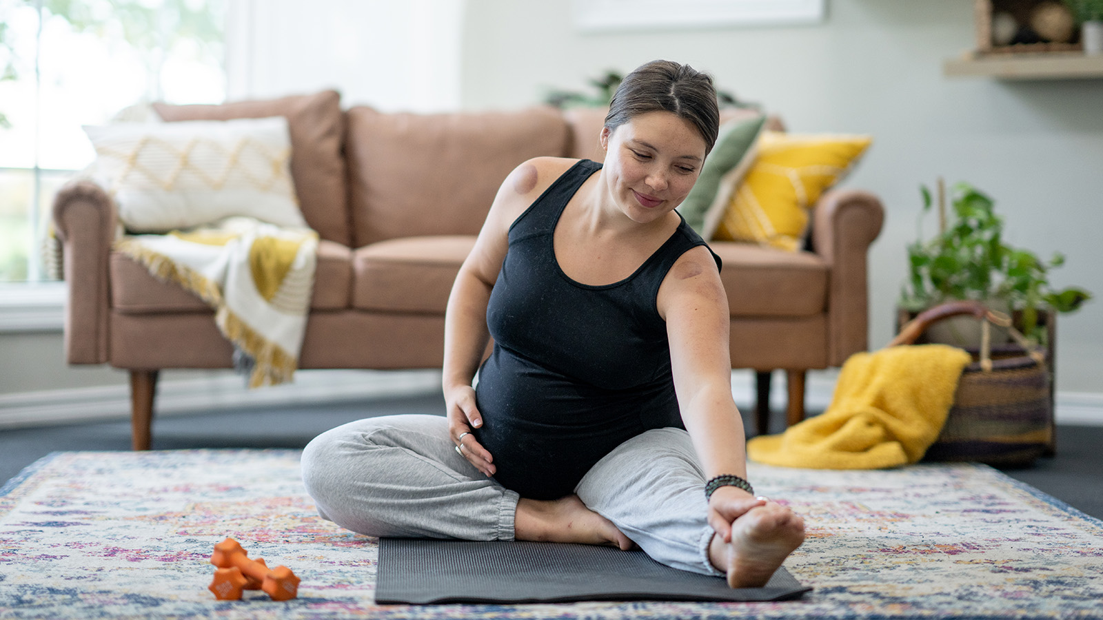 Pregnant woman stretching on an exercise mat in her living room