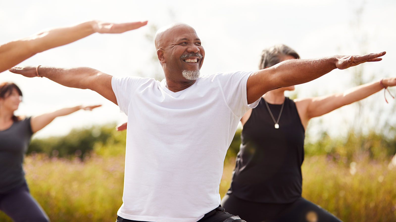 Group of middle aged people enjoying an outdoor yoga class