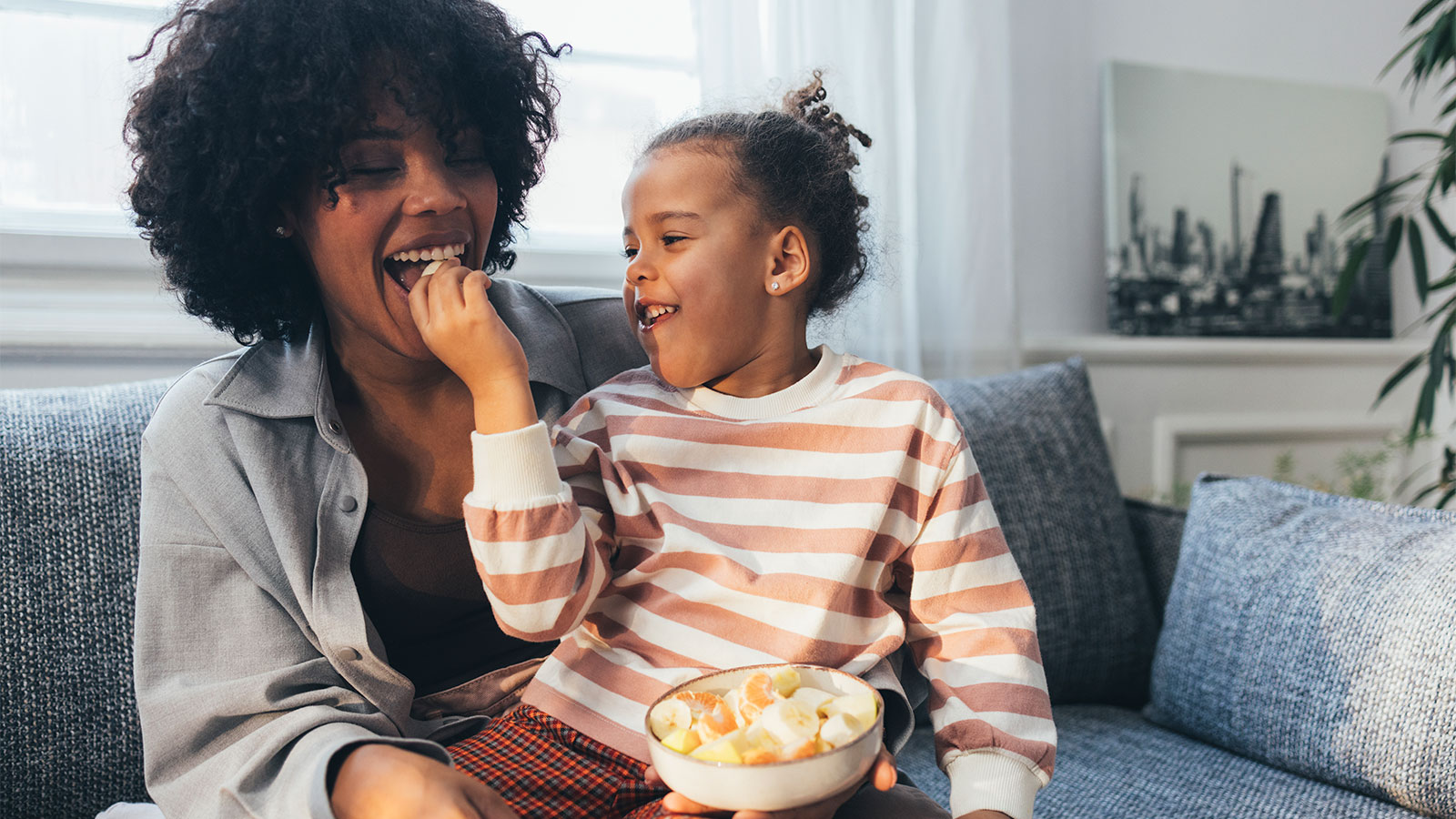 mom and daughter sitting on couch snacking