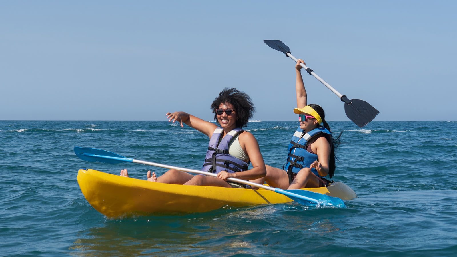 Two women kayaking on a calm ocean