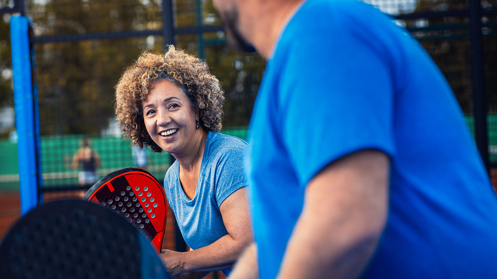 middle aged woman smiling and talking outside of pickle ball court