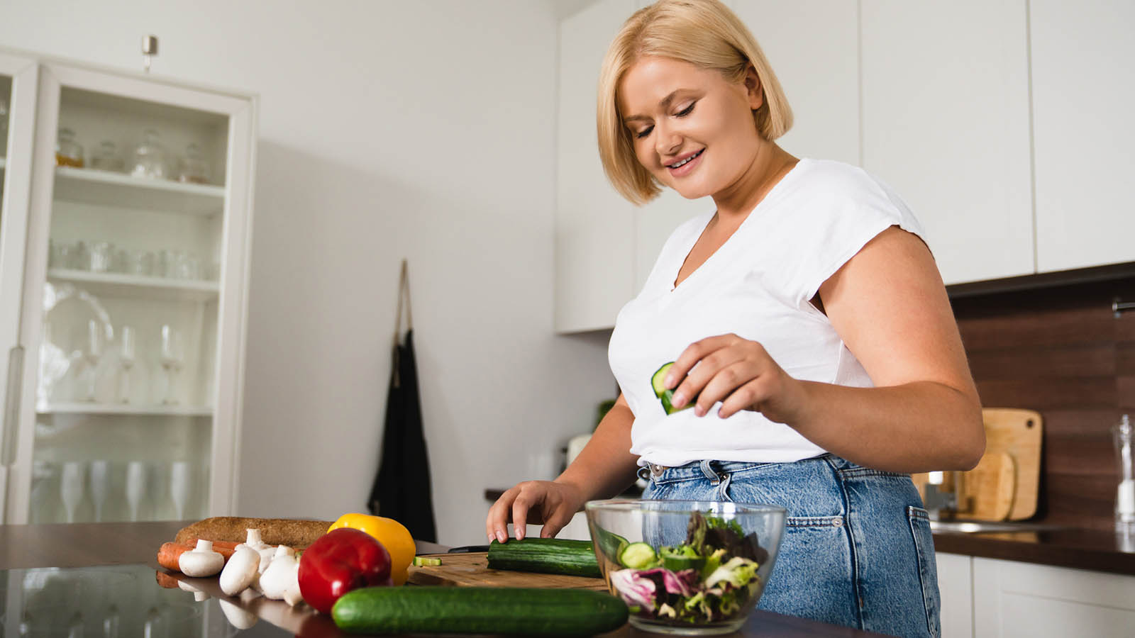 woman in kitchen making a salad