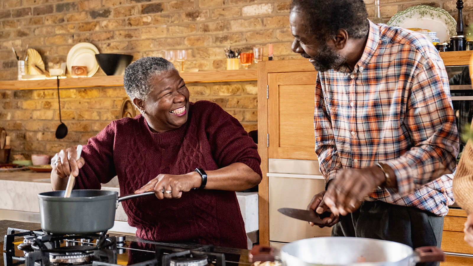 Senior couple preparing a meal over a kitchen stove