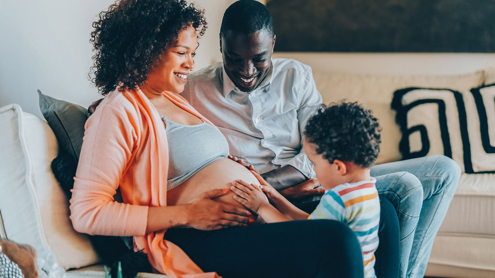 pregnant mother and father enjoying time with their young son