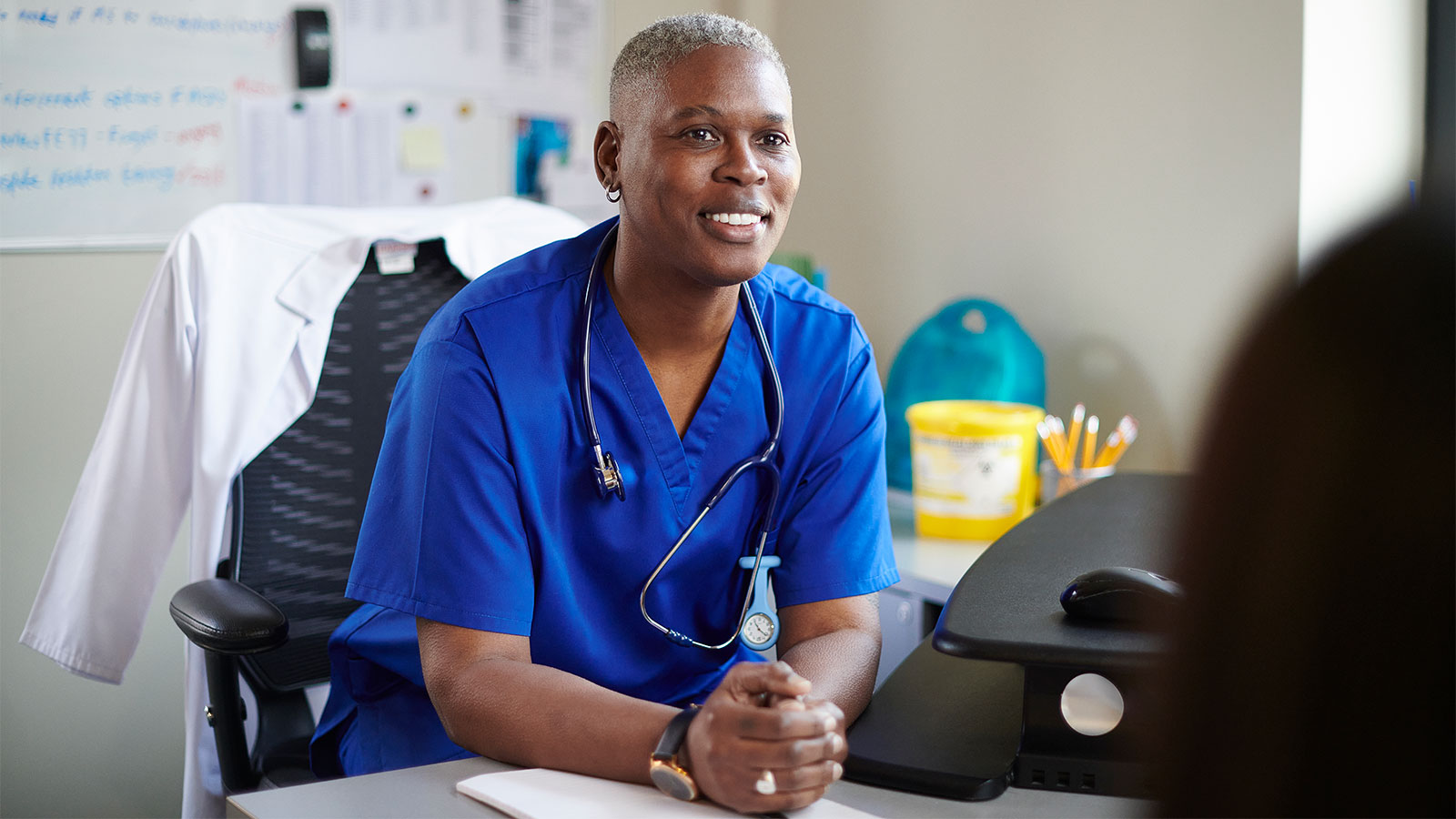 young doctor having a conversation with her patient in her office