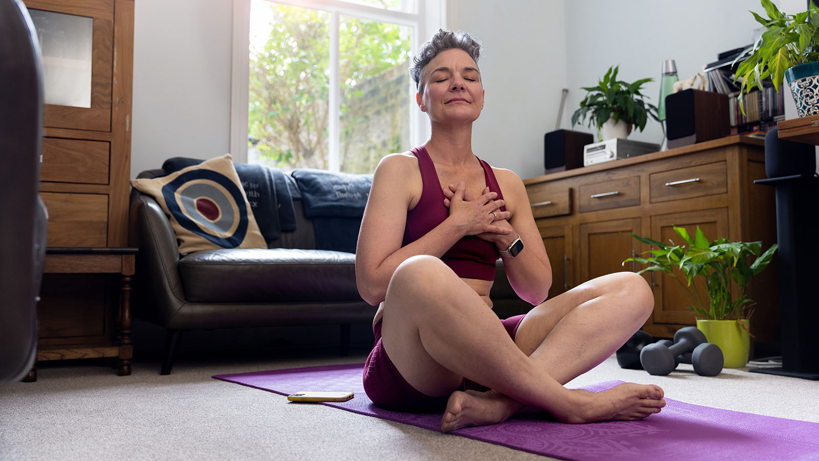 middle-aged woman meditating and doing yoga at home