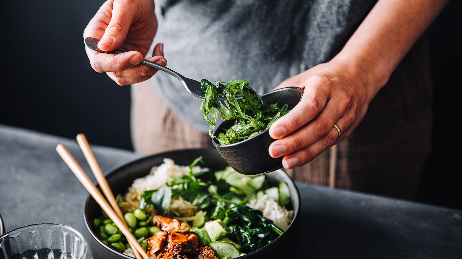 serving a bowl of rice and green vegetables with chopsticks
