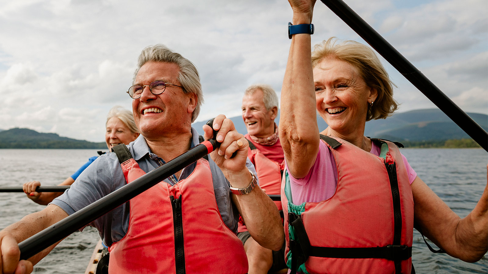 a group of happy senior friends kayaking on a lake
