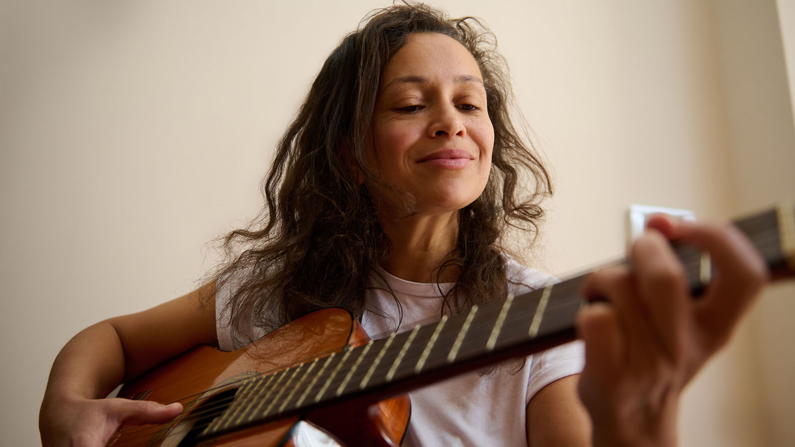 Middle aged woman smiling while playing guitar