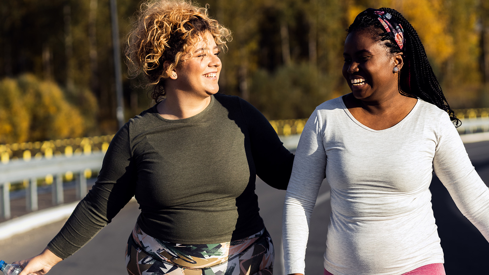 Two women smiling at each other while walking outdoors