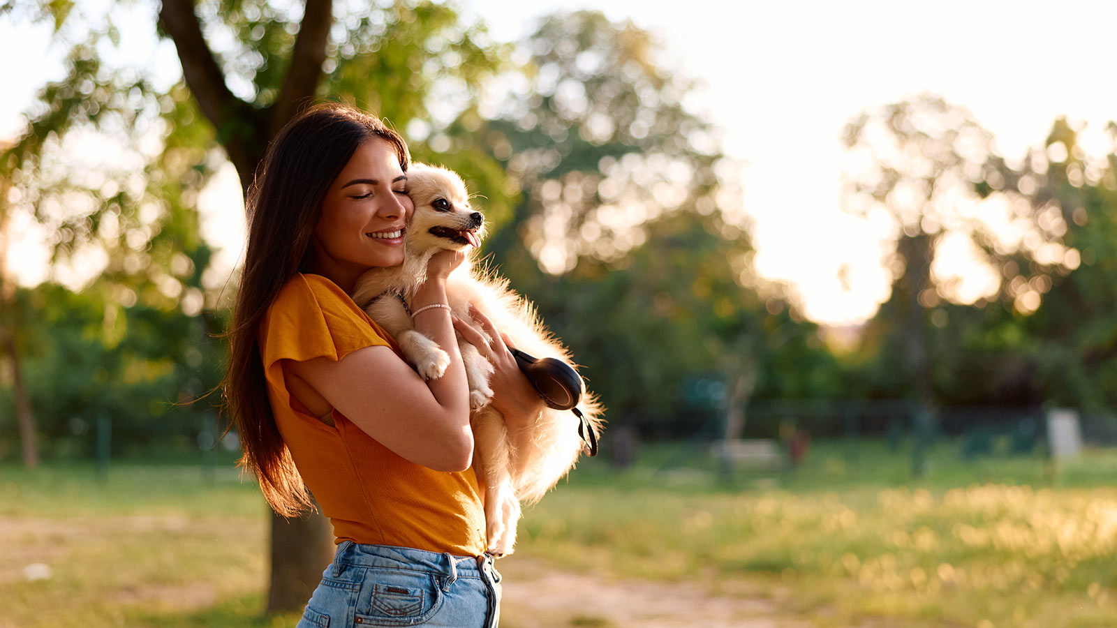 woman smiling and holding small dog in outdoor setting 