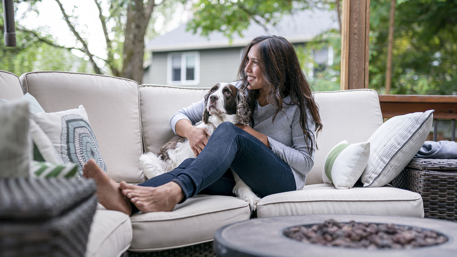 Mid-40s woman relaxing on outdoor couch with her dog