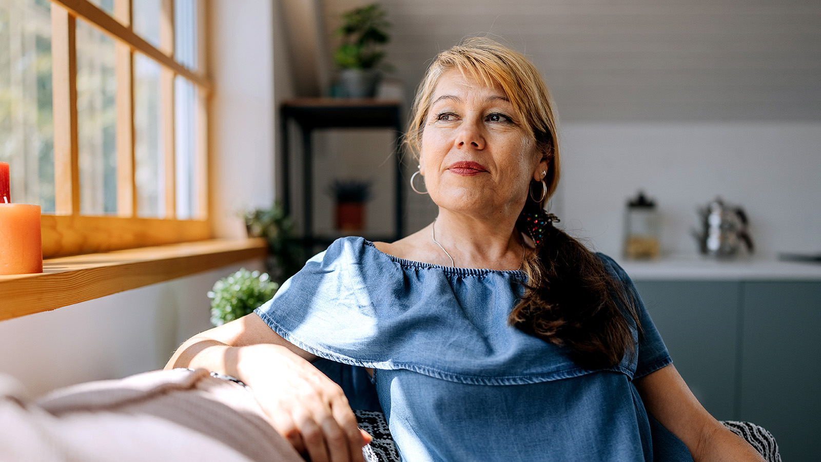 Middle-aged woman sitting on sofa and looking out window