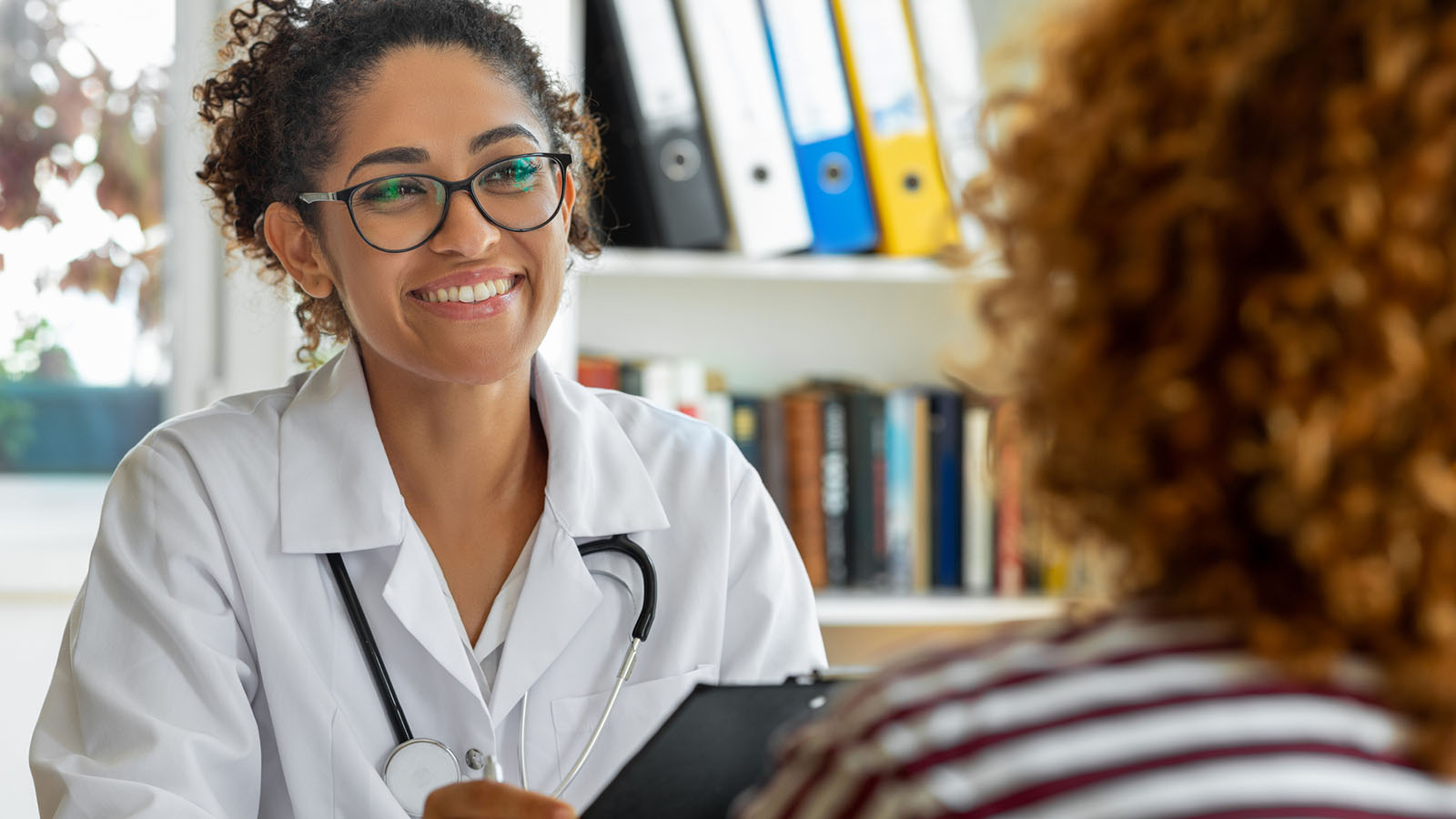 Female physician smiling and speaking with a female patient