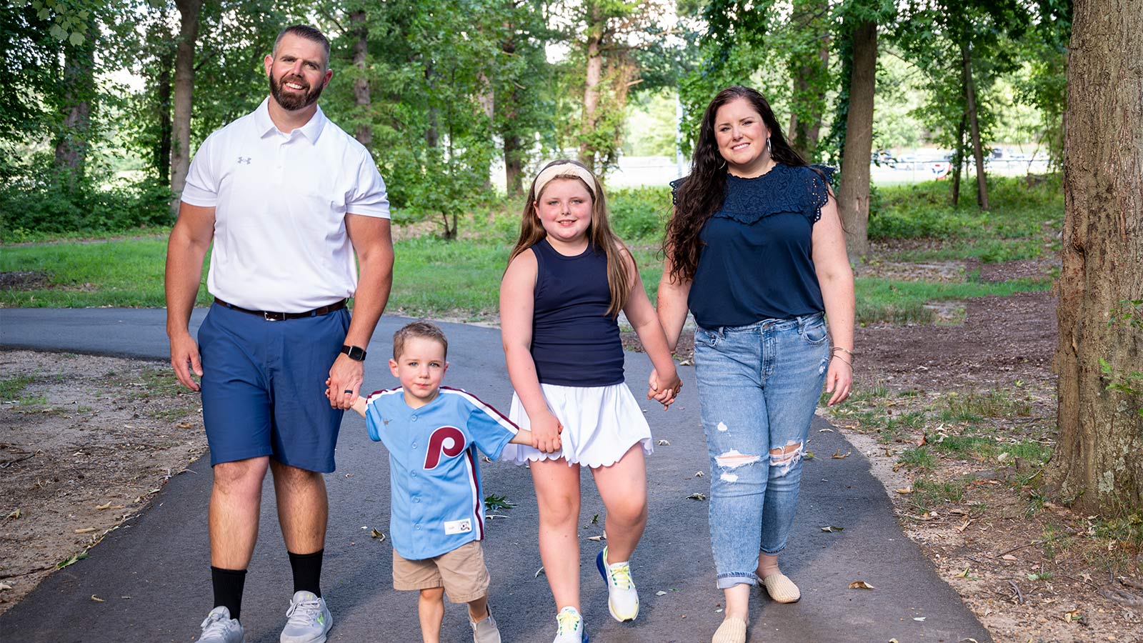 Family holdng hands and walking on path in a park
