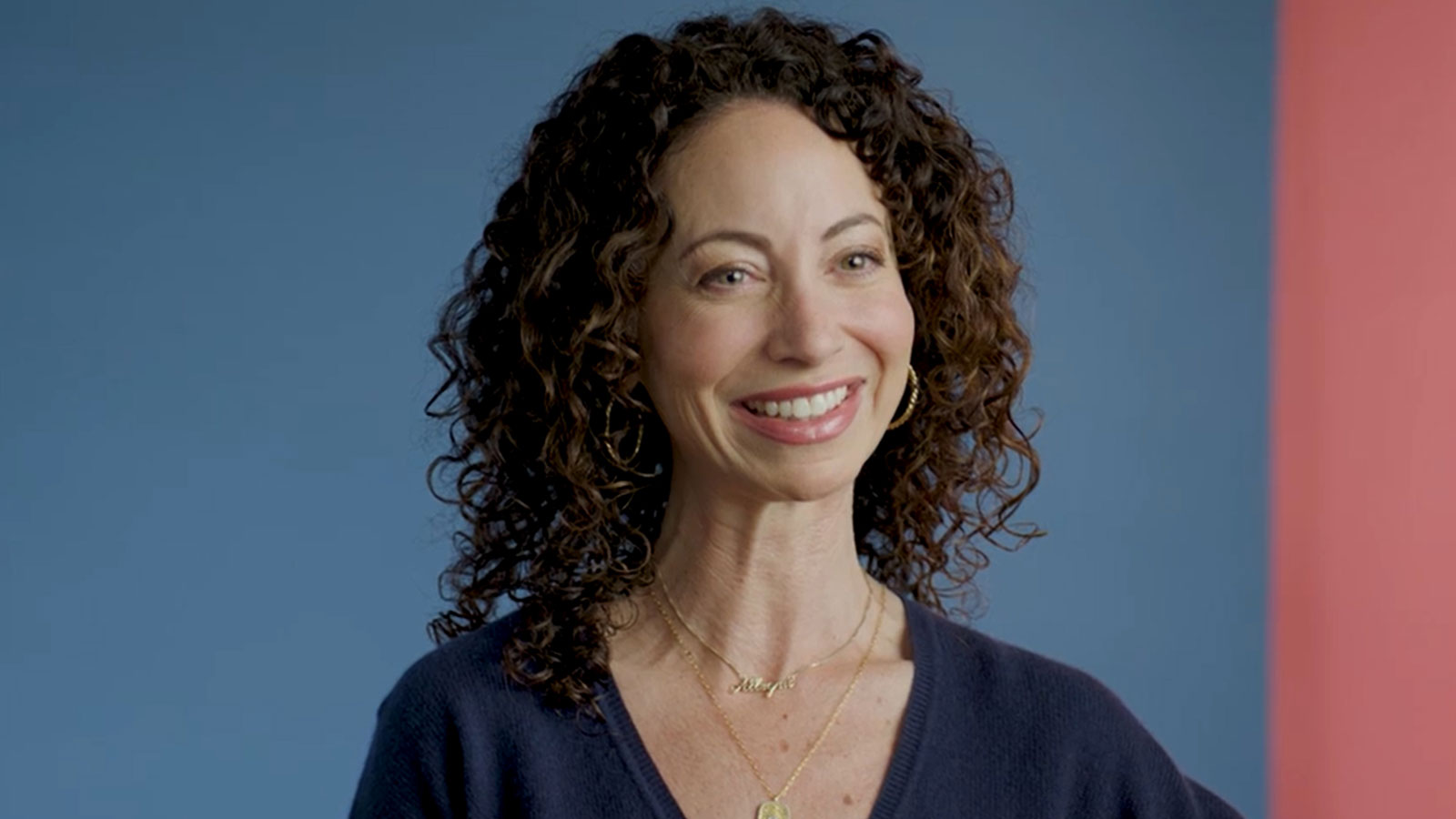 Headshot of a woman, smiling in front of a colorful background