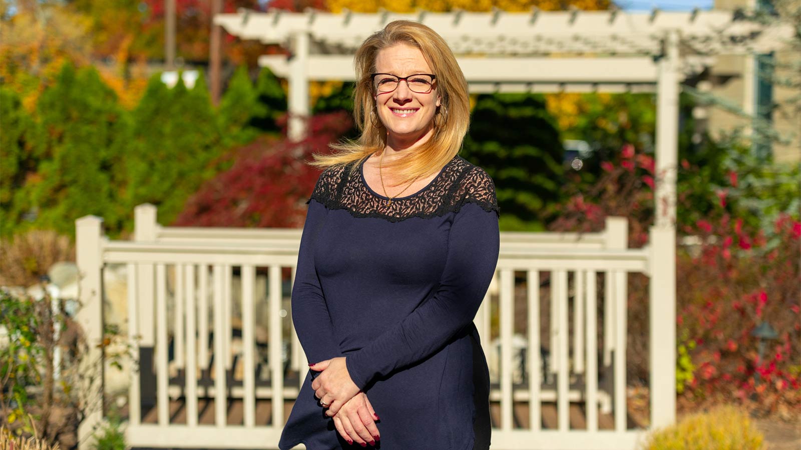Woman standing in front of pergola in garden and smiling