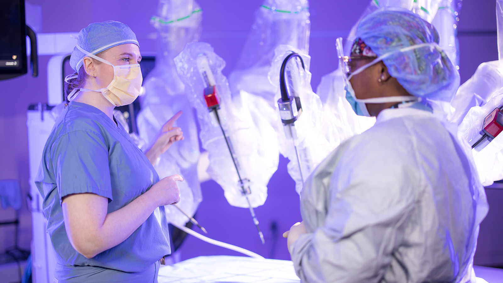 two doctors with surgical gear talking in front of Stryker Mako device