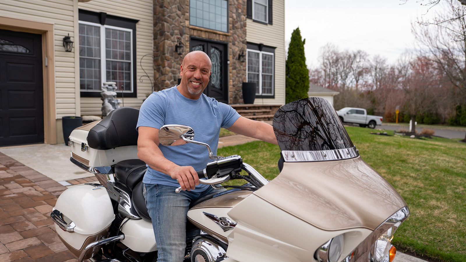 Male Virtua Health patient poses on his motorcycle in front of his home