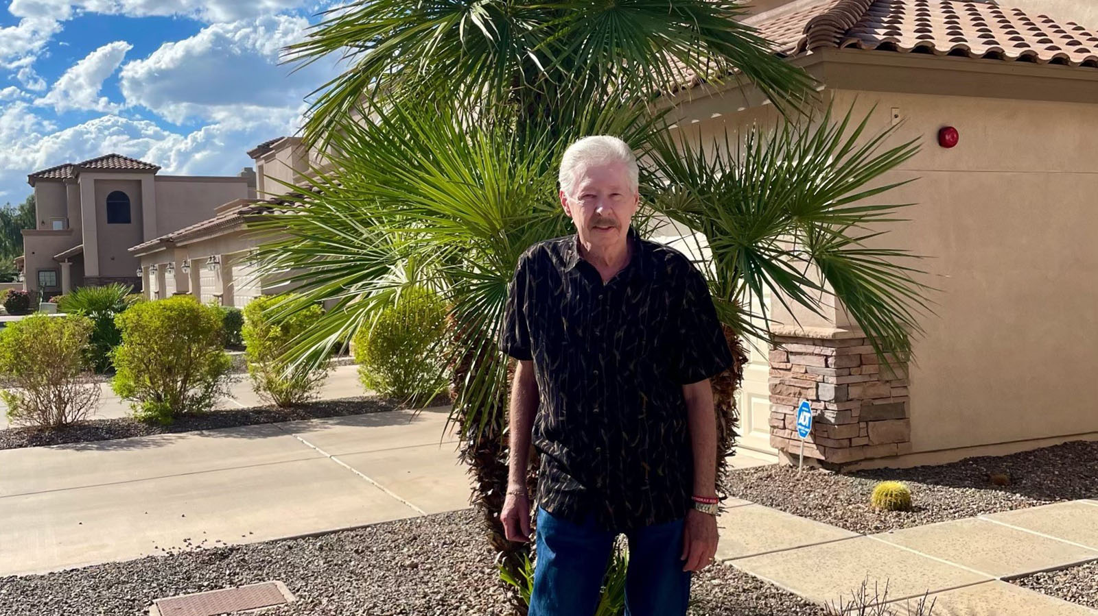 Older male standing in front of Spanish-style house in Arizona