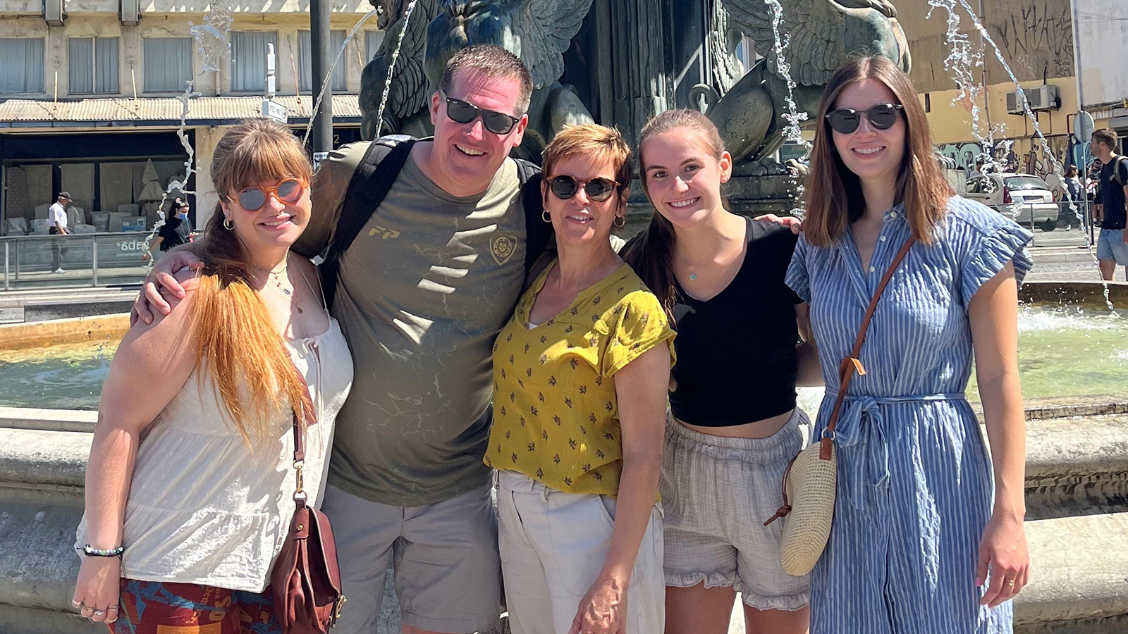 Middle aged man, wife and children posing in front of fountain